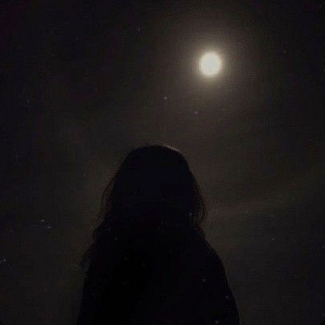 a person standing in the dark looking at the moon