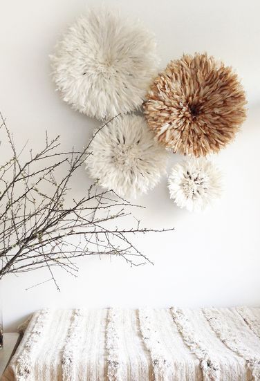 three white and brown pom - poms hang on the wall above a bed