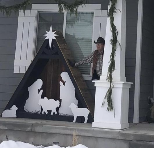 a man standing on the front steps of a house next to a nativity scene