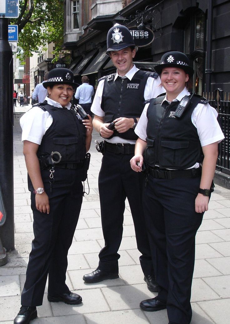 three police officers are standing on the sidewalk smiling at the camera while holding something in their hands