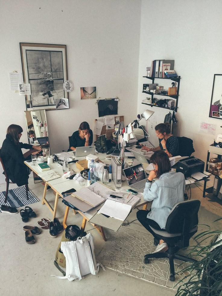 a group of people sitting around a table with papers and pictures on it in an office