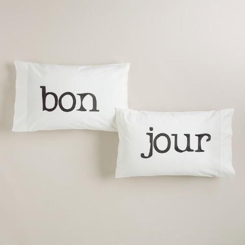 two pillows with the words bon and jour printed in black on them against a white wall