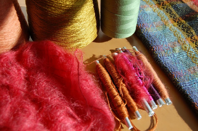 several different colored spools of yarn next to each other on a wooden table