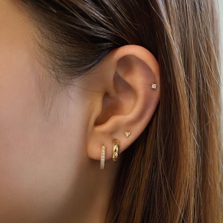 a close up of a woman's ear with two small gold earrings on it