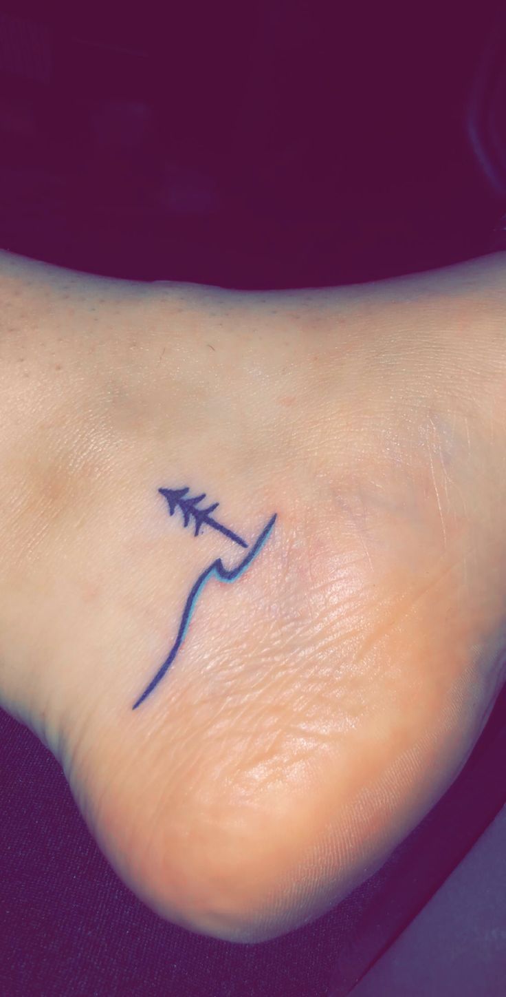 a small tattoo on the foot of a woman with an arrow in her left side