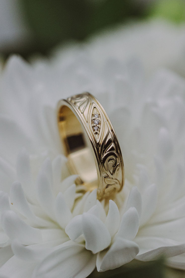 A 14K yellow gold mens' engagement band sits on a white chrysanthemum flower. This band features floral filigree details and three diamond accents. White Gold Engagement Rings For Men, Nature Inspired Wedding Ring Men, Vintage Wedding Rings Mens, Wedding Rings Engagement For Men, Mens Wedding Rings Unique Diamonds, Custom Wedding Bands For Men, Wedding Groom Ring, Men’s Wedding Ring Diamond, Unique Engagement Rings For Men Future Husband