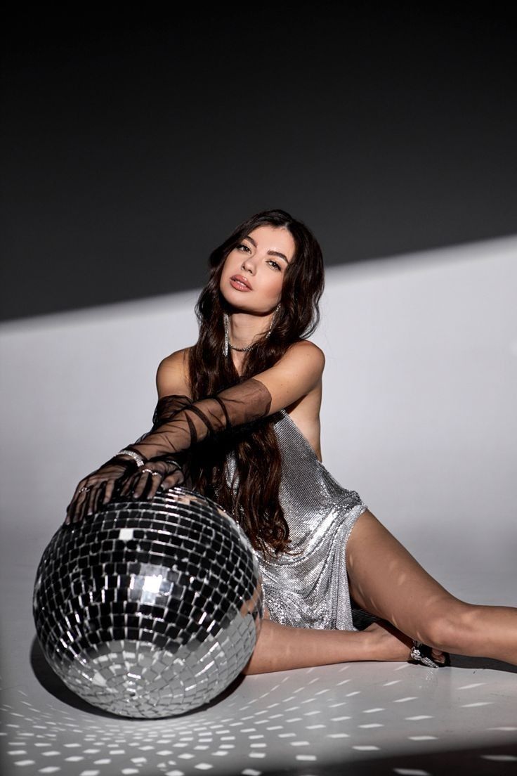 a woman sitting on the ground with a disco ball