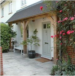 a white house with pink flowers on the front door and side walk leading up to it