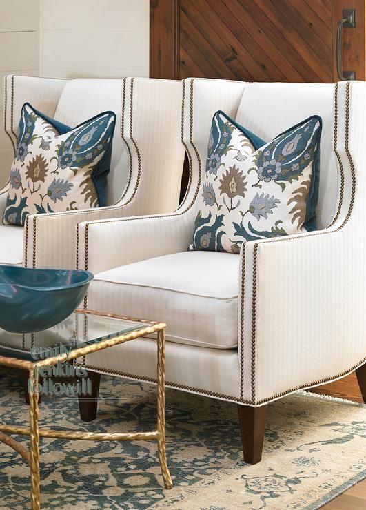 a living room with two chairs and a glass bowl on the coffee table in front of it