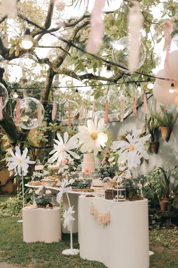 an outdoor party with balloons, flowers and cake