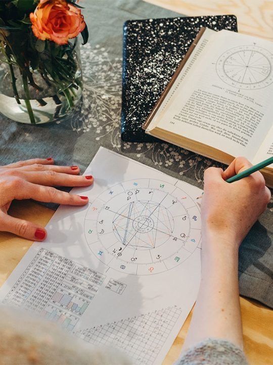 a person sitting at a table with an open book and pen in front of them