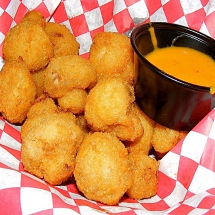 some fried food on a red and white checkered table cloth next to a bowl of soup