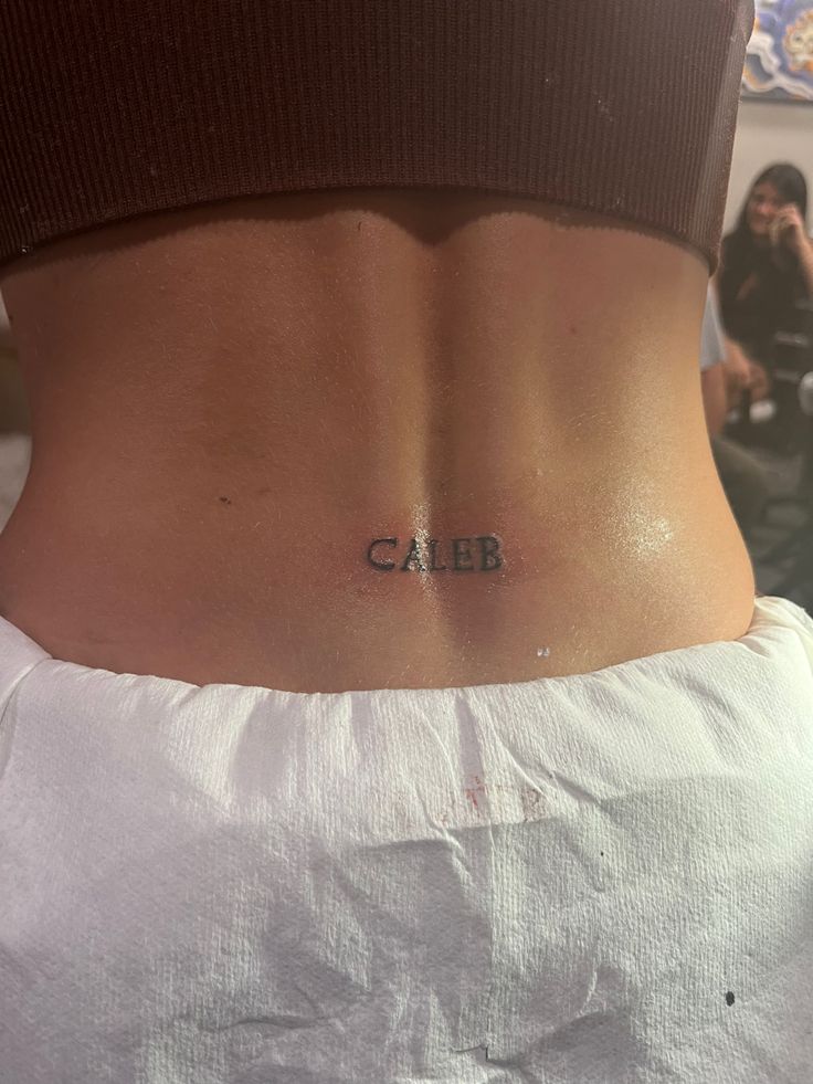 a woman's back with the word cabb tattooed on her left side ribcage