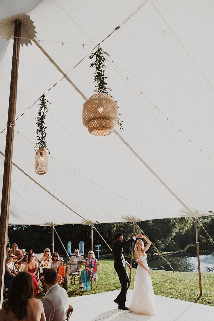 a bride and groom are dancing under a tent at their wedding reception in front of an audience