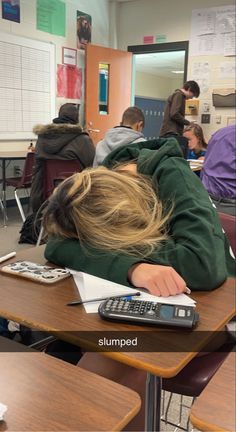 a person sleeping on top of a desk with a calculator