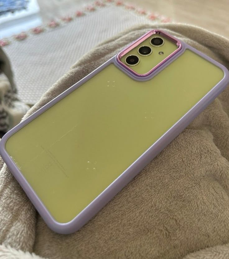 a yellow and purple case sitting on top of a bed next to a gray cat