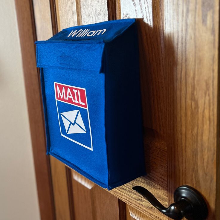 a mail box hanging on the side of a wooden door with a hook in it