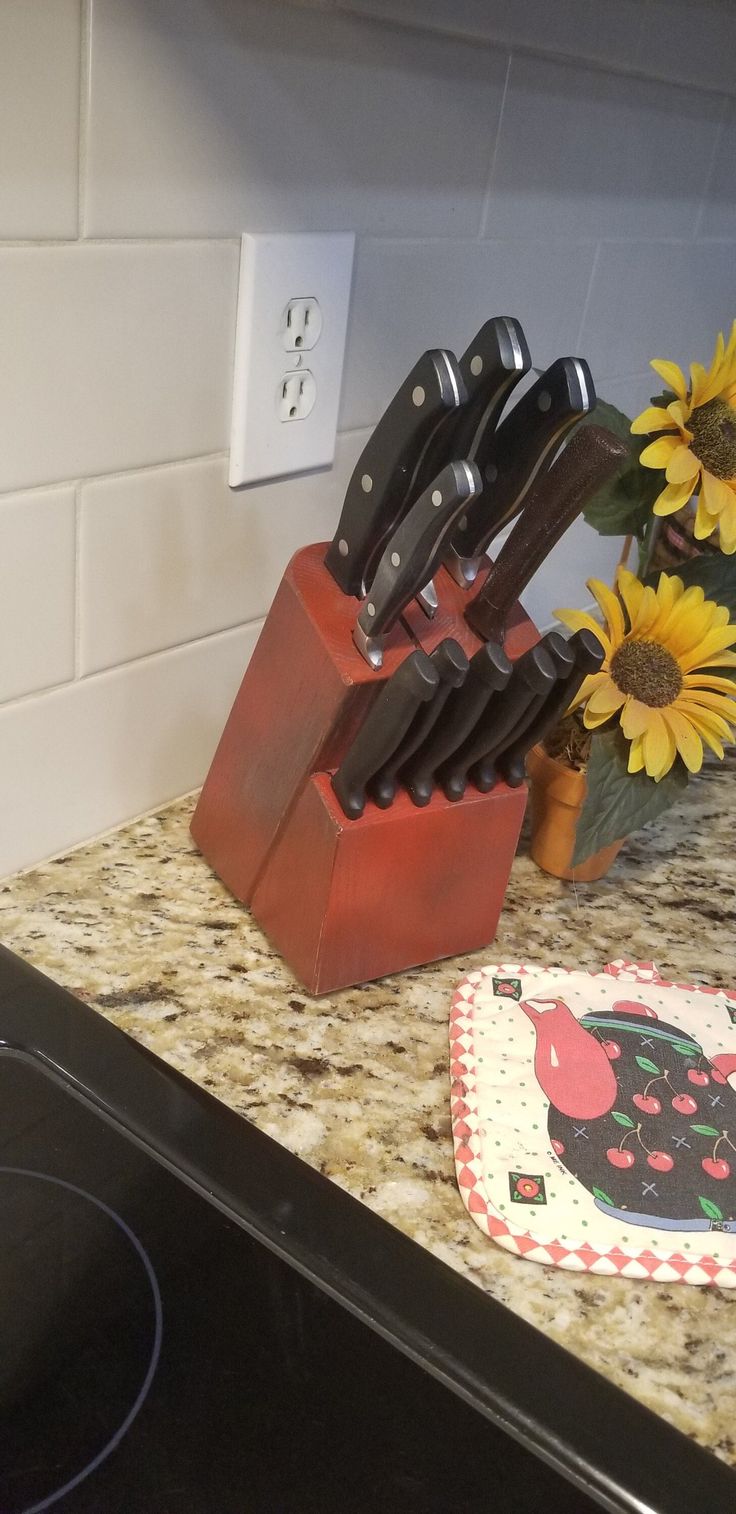 a kitchen counter topped with lots of knives next to a vase filled with sunflowers