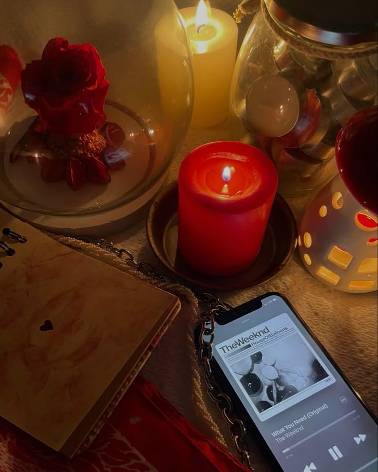 a cell phone sitting on top of a table next to some candles and other items