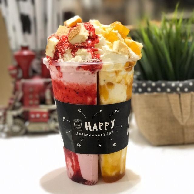 two cups filled with ice cream and fruit sitting on top of a table next to a potted plant