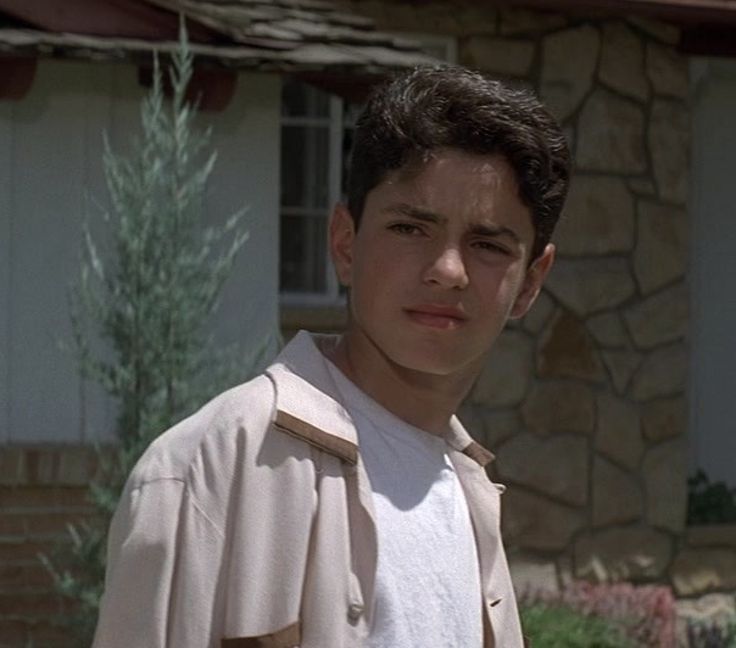 a young man standing in front of a house