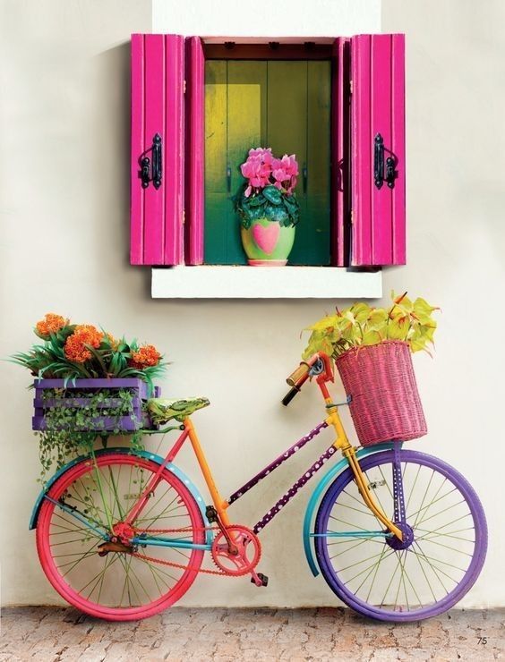 there is a colorful bike parked next to a window with pink shutters on it