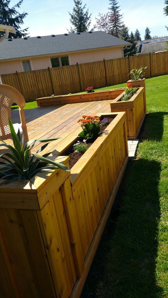 a wooden planter box with succulents and plants in it on the lawn