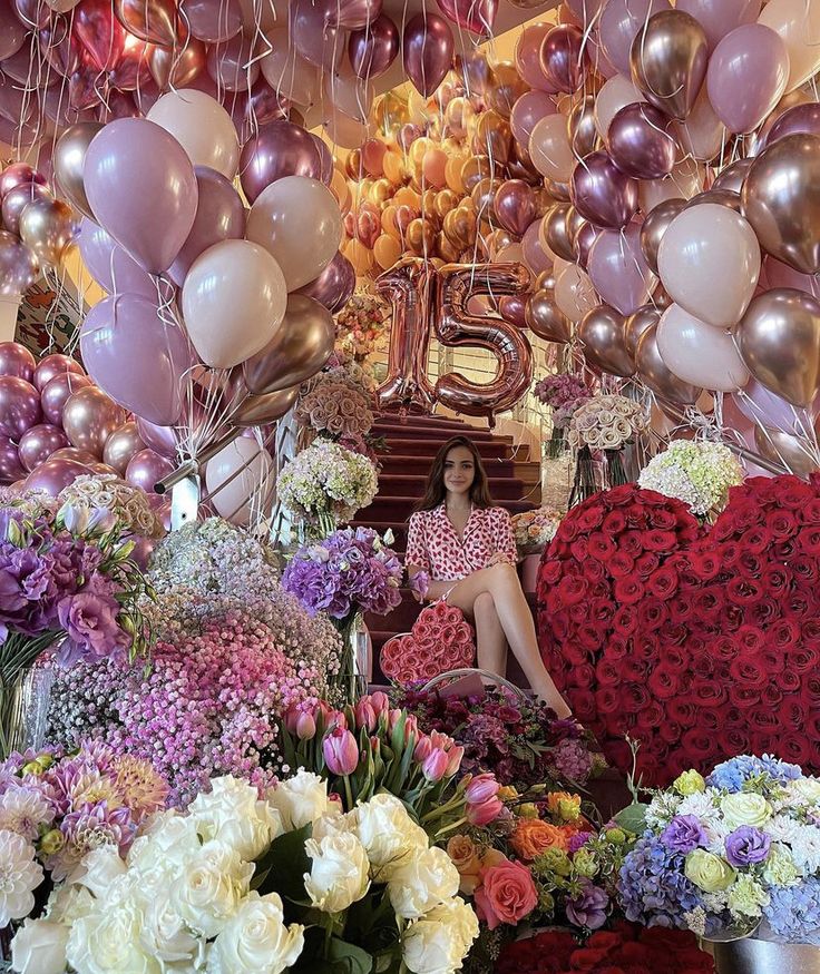 a woman sitting on a bench surrounded by flowers and balloons