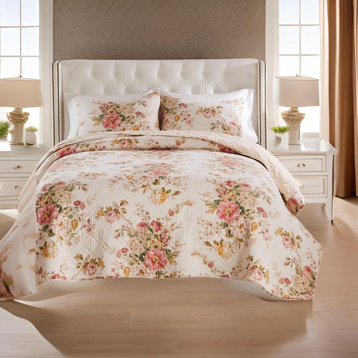 a white bed with floral comforter and pillows