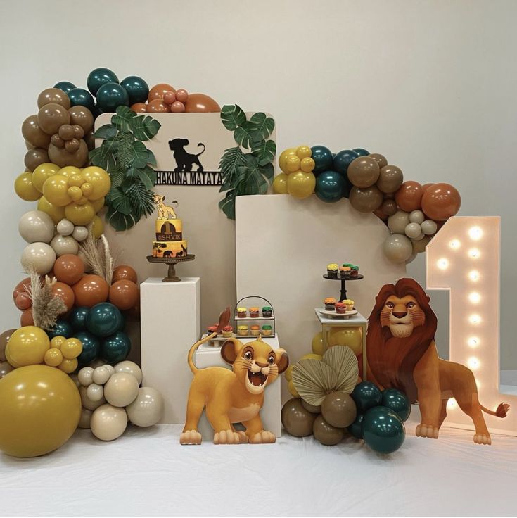 a lion themed birthday party with balloons and decorations on the table, including an arch