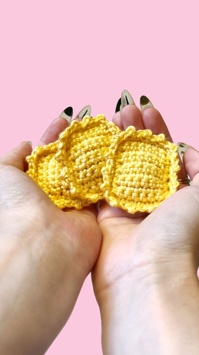 two hands holding an object made out of crochet