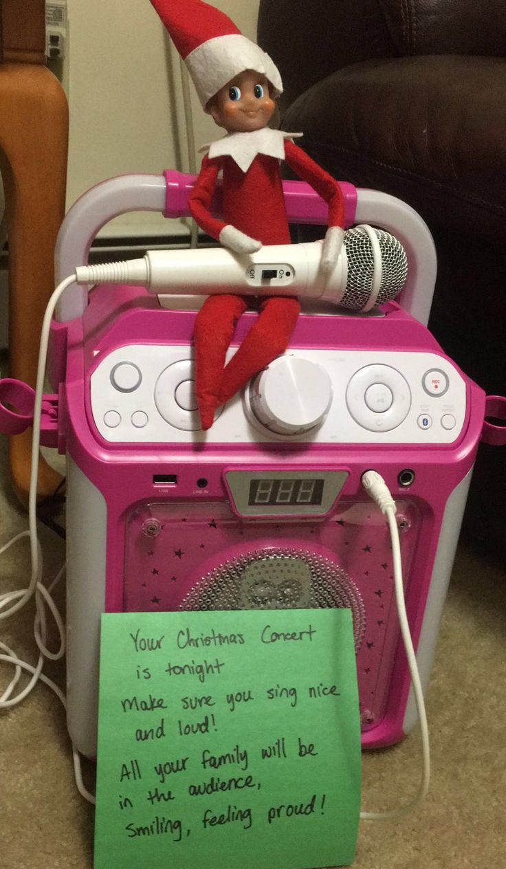 an elf is sitting on top of a pink stove with a note attached to it