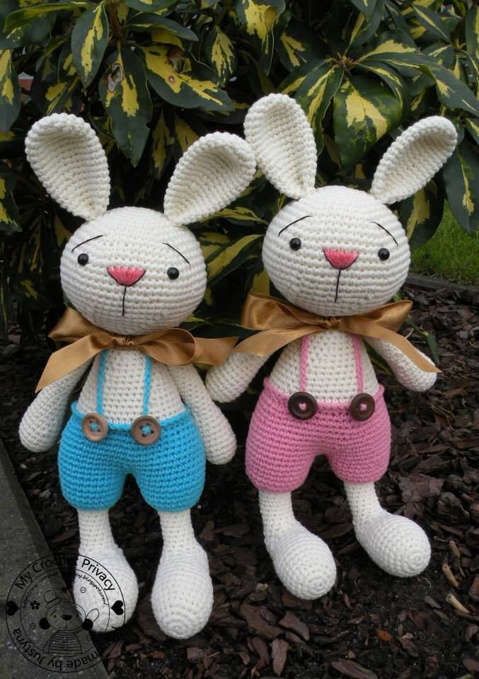 two crocheted stuffed animals sitting next to each other in front of some plants