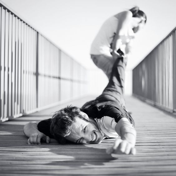 two men are laying on the ground and one is holding his leg up