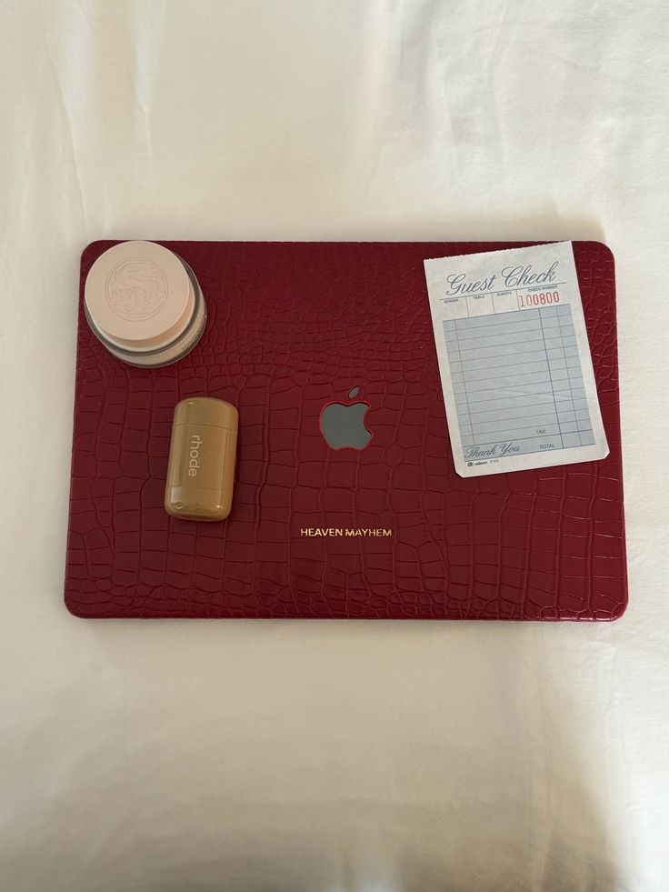 an apple, soap and other items are sitting on a red tray with white sheets