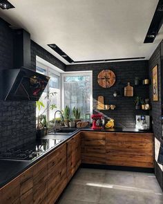 a kitchen with black brick walls and wooden cabinets is pictured in this image, there are plants on the counter