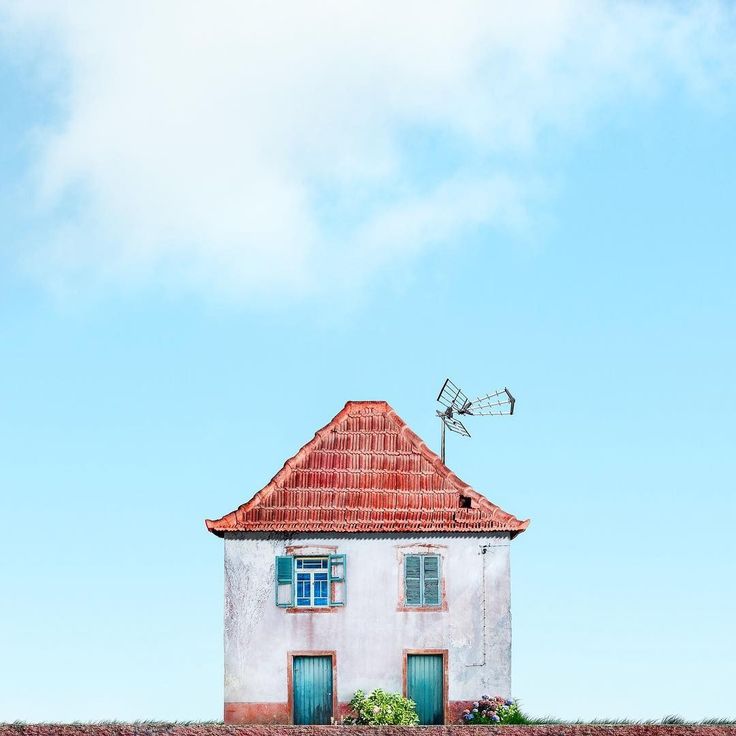 a white house with a red roof and green shutters on the windows is in front of a blue sky