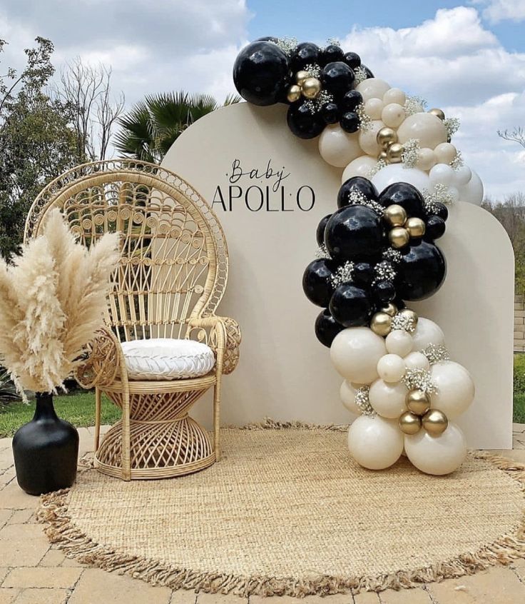 balloon arch with black, white and gold balloons on display in front of a sign