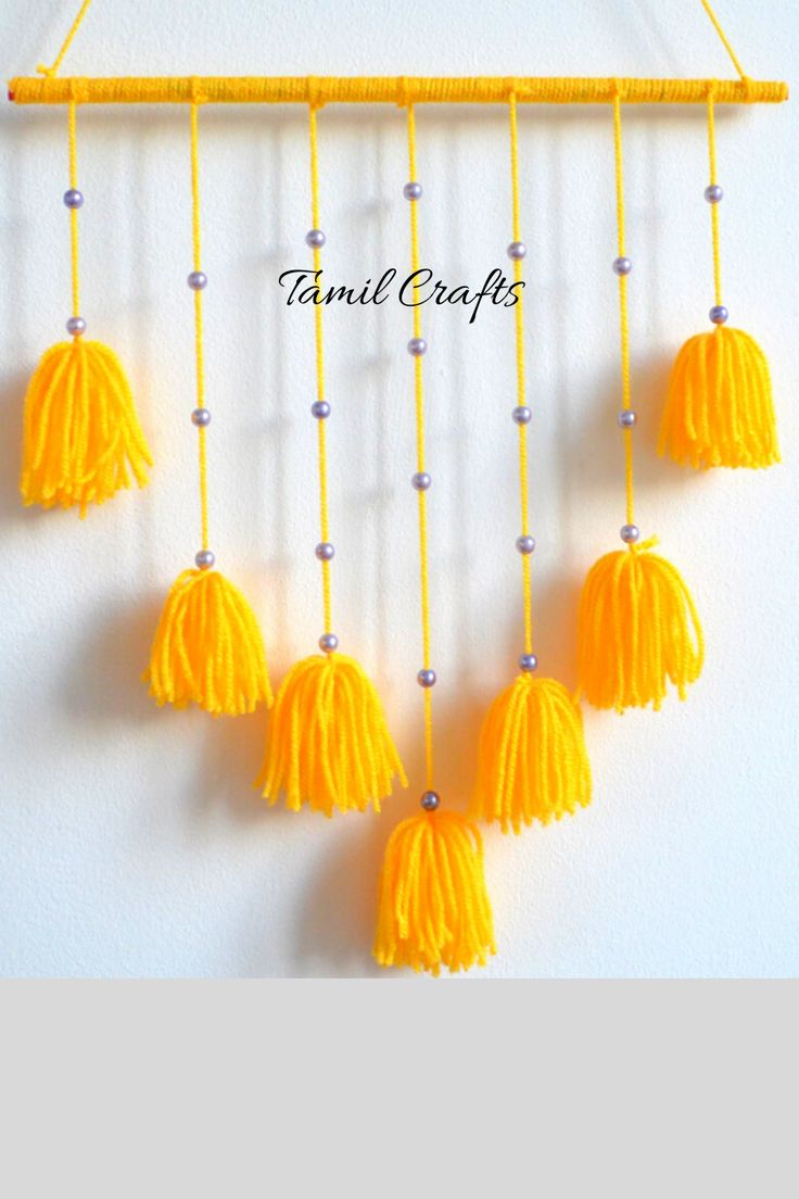 a yellow and white wall hanging with tassels on the end, next to a sign that says tamul crafts