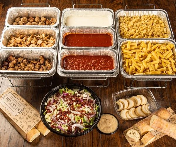 several trays filled with different types of food on top of a wooden table next to crackers