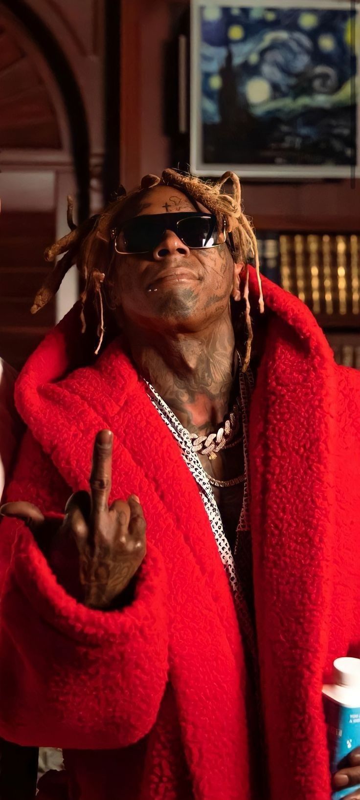 a man with dreadlocks wearing a red robe and sunglasses giving the peace sign