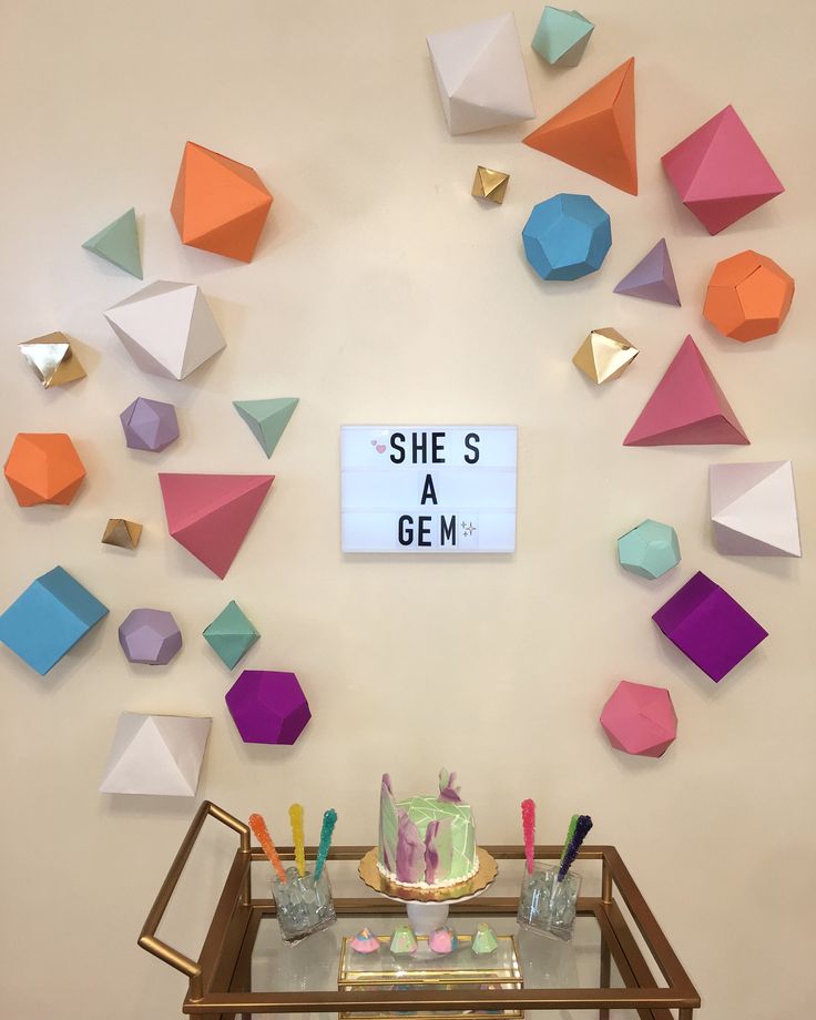 there is a cake on the table in front of some colorful paper origami