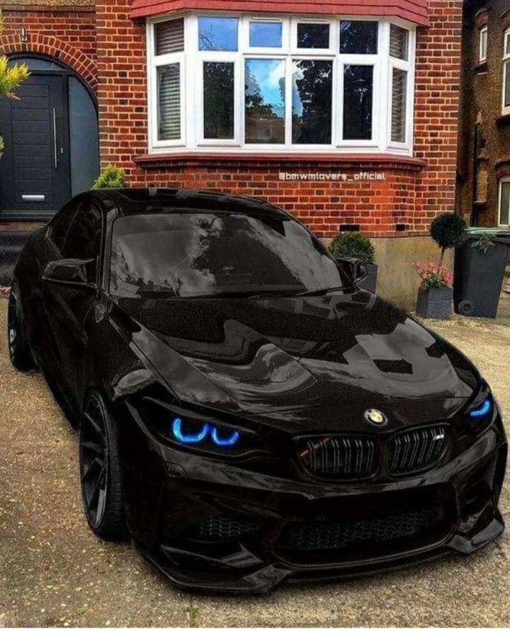 a black car with blue eyes parked in front of a house