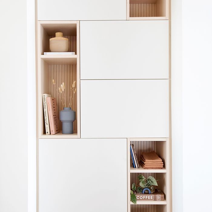 shelves with books and other items on them in a white walled room, against a wall