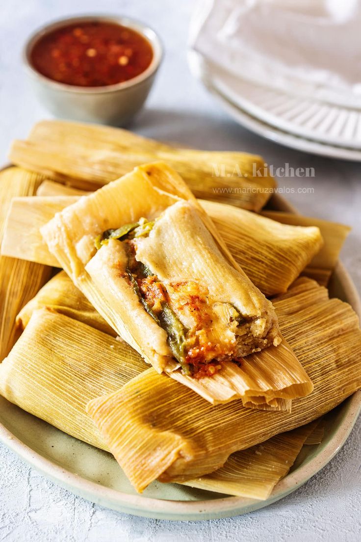 some tamales are on a plate with dipping sauce