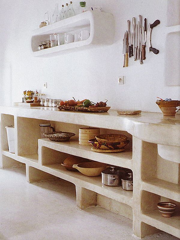 a kitchen filled with lots of counter top space and white counters topped with bowls, pans and utensils