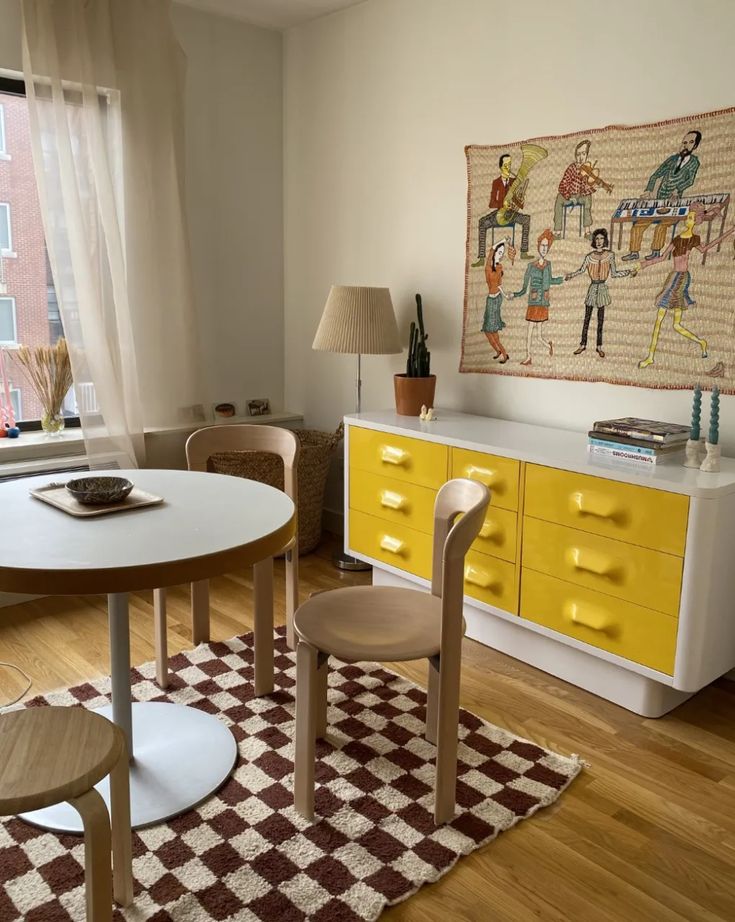 a living room with yellow furniture and a checkered area rug on the wooden floor