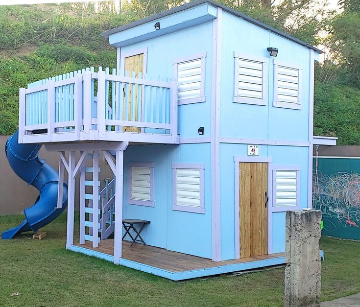 a blue house with a slide in the yard