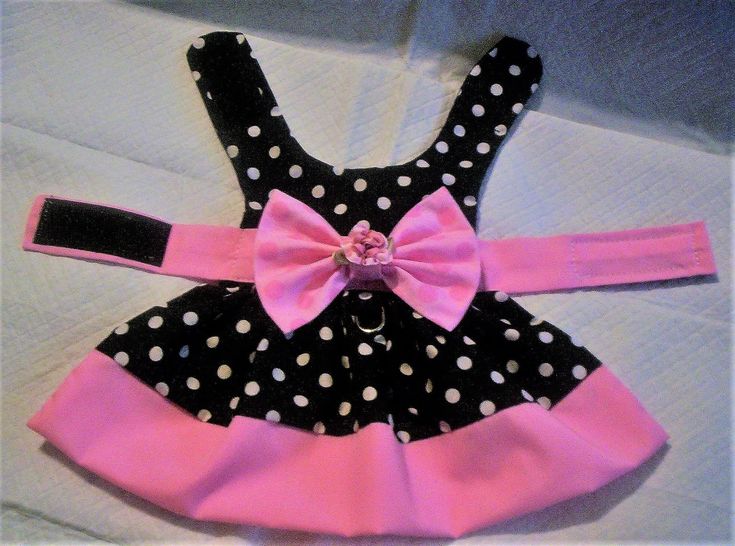 a black and white polka dot dress with pink bow on the front, sitting on top of a bed