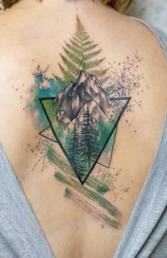 a woman's back with a mountain and pine tree tattoo on it